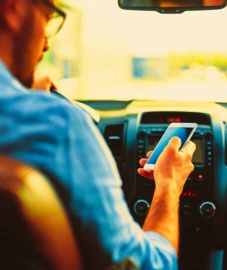 man using phone while driving the car