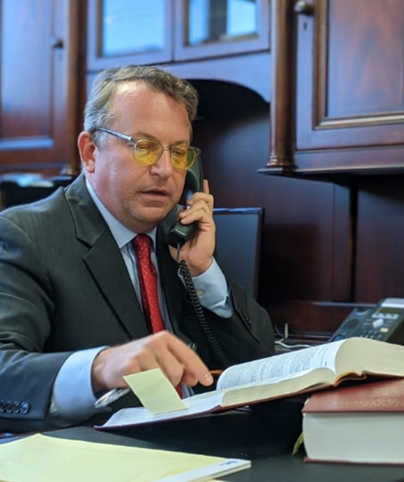 gentleman talking on the phone while reading a book with a sticky note