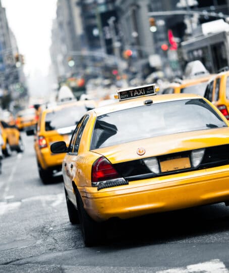 a New York taxi with a blurry background of traffic jam