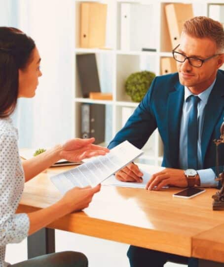 lawyer and client looking at each other while discussing papers in office