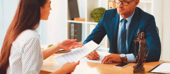 lawyer and client looking at each other while discussing papers in office