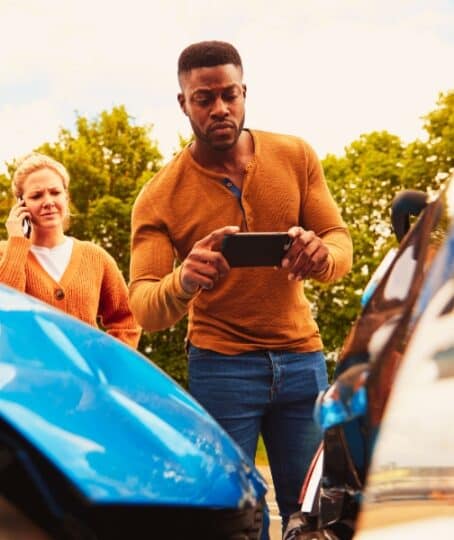 Male Motorist Involved In Car Accident Taking Picture Of Damage For Insurance Claim