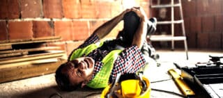 an injured construction worker holding his knee and in pain