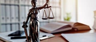 Lady Justice statue in law firm attorney office, blindfolded Justitia with balance scales and sword is personification of moral force in judicial system