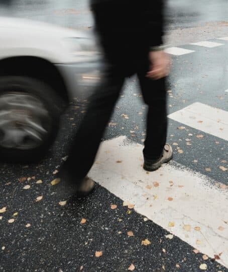 Man on pedestrian crossing in autumn, in danger of being hit by car