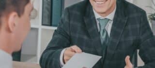 businessman in blue jacket taking paper from worker with broken arm. concept of lost wages