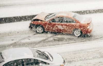 A red car has slid on the icy road. Concept of Who Is Liable for a Car Accident Due to Weather Conditions