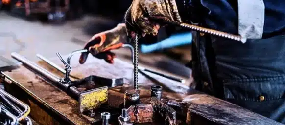 Close up shot of metallurgy worker's hands doing metal works.