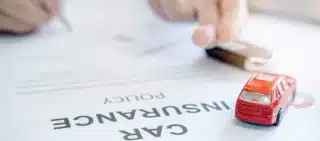 Car insurance policy with red car toy and blur image of man hand for vehicle insurance policy.