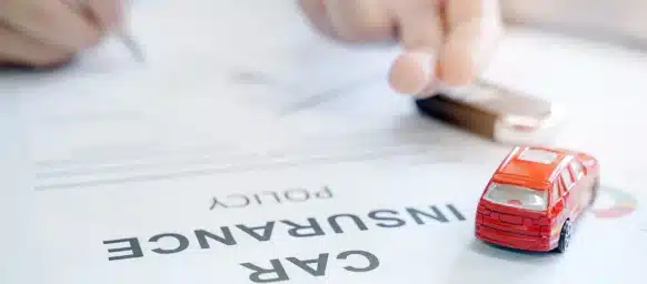 Car insurance policy with red car toy and blur image of man hand for vehicle insurance policy.