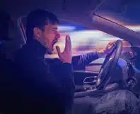 Young sleepy man is yawning and driving car at night. drowsy drivers