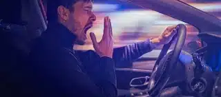 Young sleepy man is yawning and driving car at night. drowsy drivers