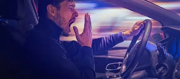 Young sleepy man is yawning and driving car at night. drowsy drivers