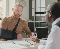 Man with hand in sling talking to his lawyer after an injury. Employer Won't Report Your Work Injury