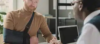 Man with hand in sling talking to his lawyer after an injury. Employer Won't Report Your Work Injury