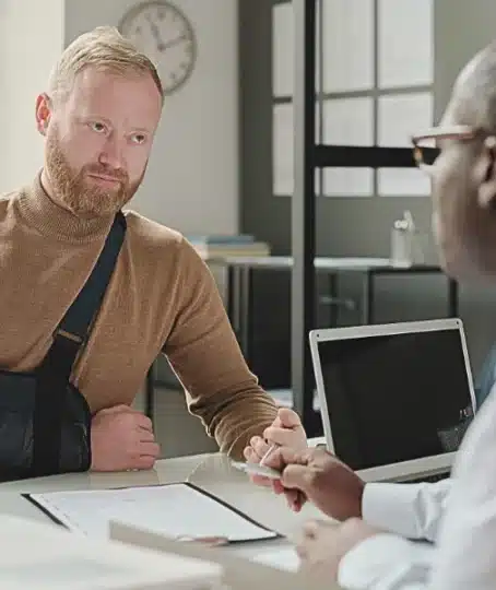 Man with hand in sling talking to his lawyer after an injury. Employer Won't Report Your Work Injury