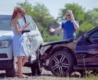Aftermath of a minor two-car collision, where the drivers are handling the situation and reporting the accident. What Happens If the At-Fault Driver Has Only Minimum Insurance in Illinois