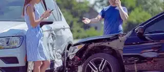 Aftermath of a minor two-car collision, where the drivers are handling the situation and reporting the accident. What Happens If the At-Fault Driver Has Only Minimum Insurance in Illinois