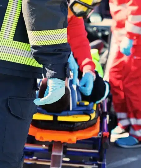 Emergency responders treating a patient on a stretcher.