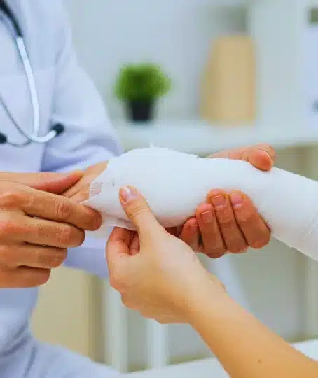 Doctor applying a white gauze bandage to patient's arm.