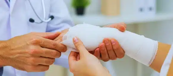 Doctor applying a white gauze bandage to patient's arm.