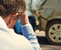 A man sits looking worried because he has just crashed into another car insurance company blames you for the accident