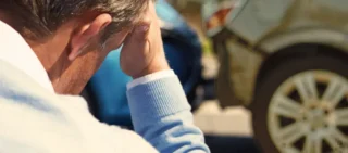 A man sits looking worried because he has just crashed into another car insurance company blames you for the accident