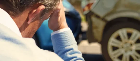 A man sits looking worried because he has just crashed into another car insurance company blames you for the accident