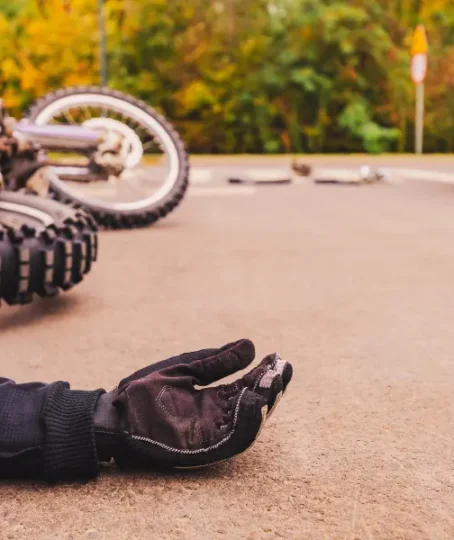 Accident on the highway involving a black car and a blue motorcycle. The motorcyclist is lying on the ground, showing his arm.