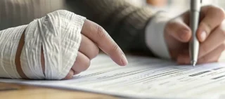 A woman's bandaged hands are holding a pen as she appears to be signing a document. gather evidence after an Illinois accident