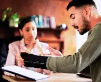 Injured man in a wrist brace speaking with a lawyer.