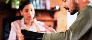 Injured man in a wrist brace speaking with a lawyer.
