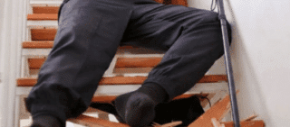 An elderly person fallen on a staircase next to broken wooden steps and a walking cane sue after falling on broken stairs